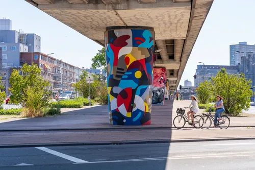 Large mural beneath Rijnhaven metro station with cyclists and pedestrians passing by.