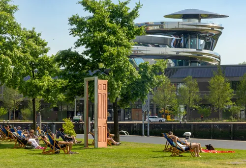 Een foto van de Tornado op het gebouw van de Fenix met op de voorgrond mensen liggend in het gras