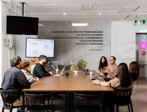 Photo of a meeting setting at 42workspace, with several people around a conference table.