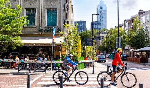 Een foto van fieters op de Witte de Withstraat met restaurant Bazar en op de achterzijde De Zalmhaventoren