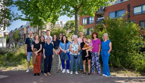 Photo of a group of people posing in a green urban environment.