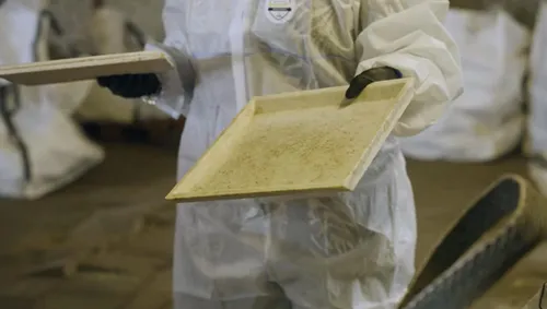 Photo of a person in safety clothing holding a sheet of recycled material