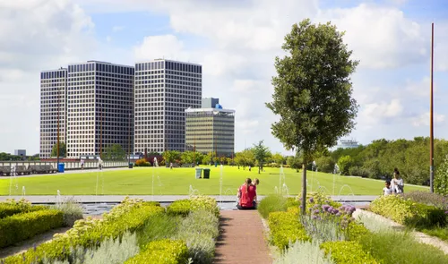 Een foto van een zittende vrouw op het Dakpark in de zomer met op de achtergrond de Marconitorens bij Marconiplein