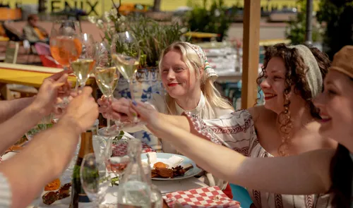 Een foto van mensen die proosten met wijn bij restaurant De Matroos en Het Meisje