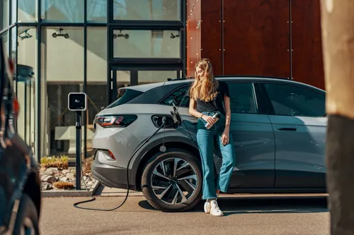 woman next to electric vehile whiles charging