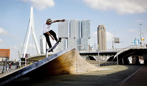 Een foto van een skater op het Willemsplein met op de achtergrond de Erasmusbrug en de Kop van Zuid