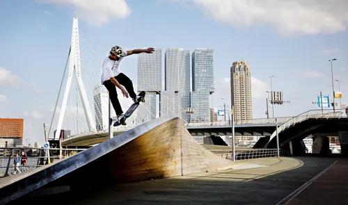 Een foto van een skater op het Willemsplein met op de achtergrond de Erasmusbrug en de Kop van Zuid