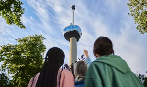 Een foto van mensen die naar de Euromast kijken en naar de top wijzen in de zomer