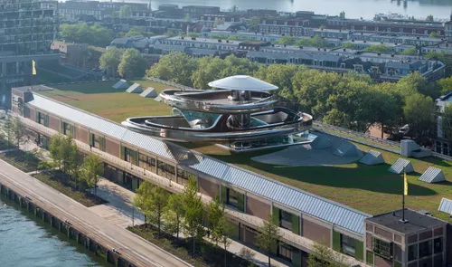Aerial view of Fenix Food Factory on Katendrecht: long waterfront building with a green rooftop crowned by a coiled spiral slide.