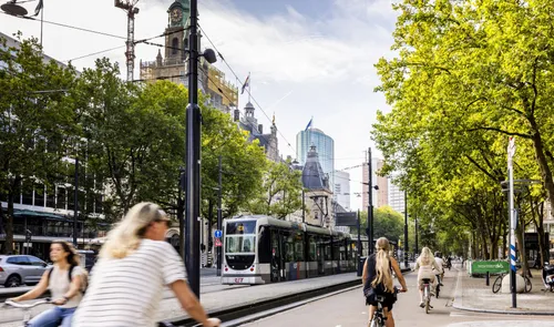 Een foto van fietsers op de Coolsingel met op de achtergrond een tram in de zomer