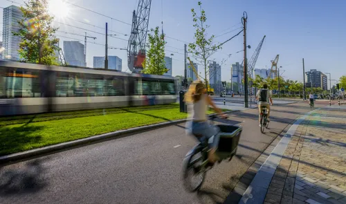 Een foto van fietsers op de Schiedamsedijk richting de Erasmusbrug met op de achtergrond een tram