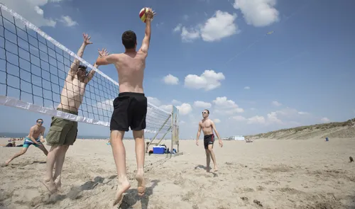 Een foto van sporters aan het volleyballen op het strand van Hoek van Holland