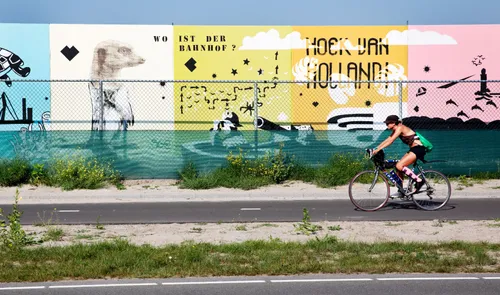 Een fietser voor een muur met muurschilderingen en street art in Hoek van Holland