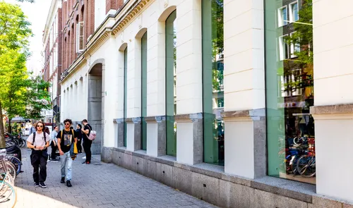 Een foto van mensen die wandelen langs Kunstinstituut Melly op de Witte de Withstraat