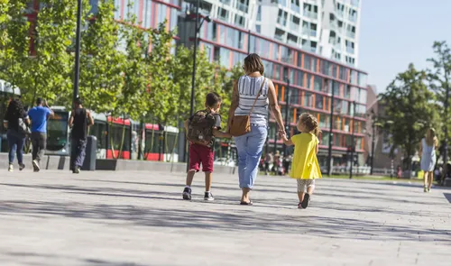 Een foto van een vrouw met twee kinderen op het Kruisplein in de zomer