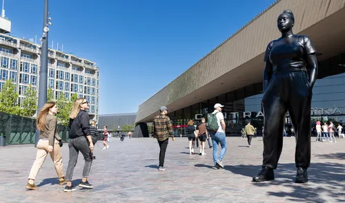 Mensen wandelen langs het kunstwerk Moments Contained op het Stationsplein