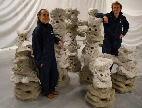 The Coastruction team proudly posing near a set of 3D printed, artificial reef structures.
