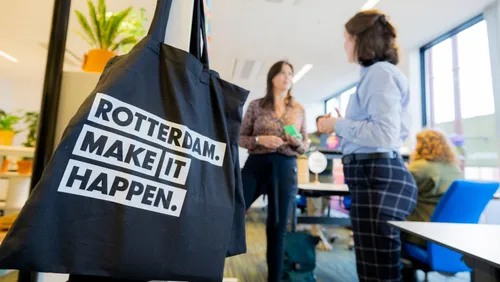 Photo: people discussing options. Rotterdam Make It Happen bag visible in the foreground.