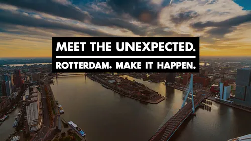 Video still of the Rotterdam Meet The Unexpected video, showing a birdseye view on the river Maas at nighttime with captions superimposed