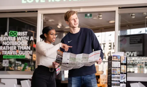 Een foto van mensen met een stadsplattegrond en een City Map die wijzen naar het Stationsplein vanaf de Rotterdam Tourist Information