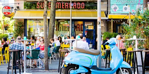 Photo of a parked moped and people at a terrace at Rotterdam's Witte de Withstraat