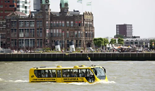 Een foto van de amfibie bus van Splashtours op de Nieuwe Maas met op de achtergrond Hotel New York