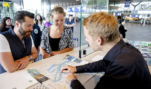 Een foto van een medewerker van de Tourist Information die bezoekers en toeristen helpt aan informatie met een City Map