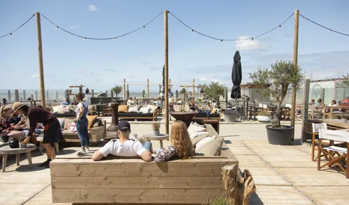 Een foto van recreanten op het terras van strandpaviljoen Uluwatu in Hoek van Holland