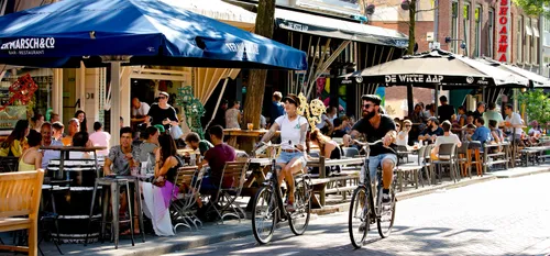 Photo: Witte de Withstraat, with people enjoying a sunny day. Cyclists pass by.