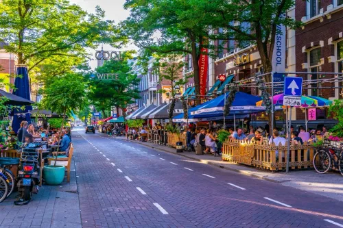 Lively Witte de Withstraat in Rotterdam with outdoor cafés, street signs, and people enjoying the vibrant atmosphere.