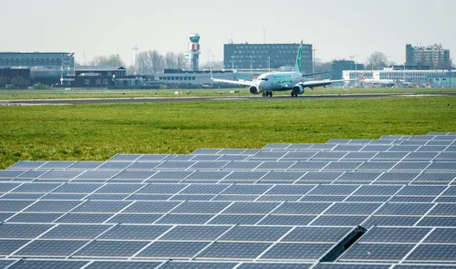 Het zonnepark met zonnepanelen met op de achtergrond een vliegtuig bij Rotterdam The Hague Airport