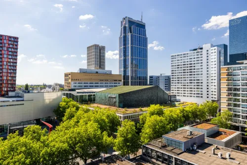 Aerial view of De Doelen concert and conference center and the Rotterdam  in Rotterdam Marriott Hotel surrounded by modern high-rise buildings and green trees.