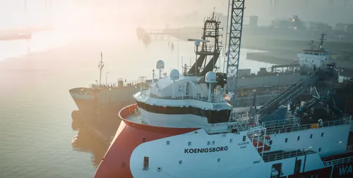 Offshore vessel Koenigsborg docked in a foggy port, equipped with Intellian satellite antennas on deck