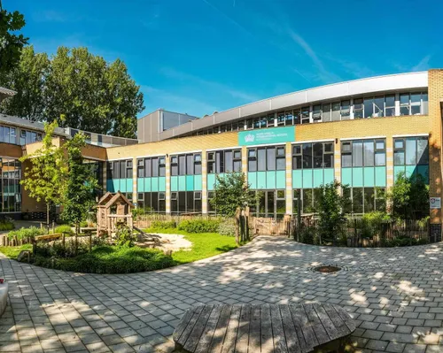 A photo of a school with some green and play garden in front of it.