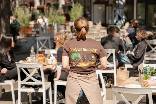 a photo of a waitress's back, with the words "Italy at first bite" written on her back.
