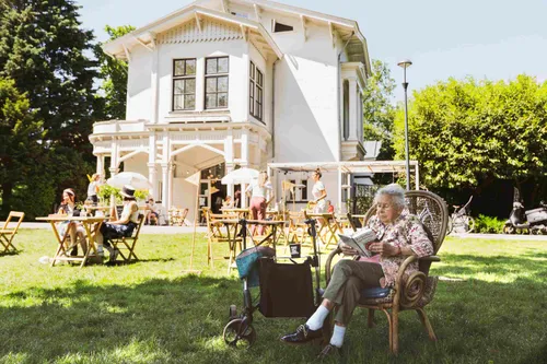 Sunny afternoon on the lawn in front of Parqiet, with guests lounging and reading under the trees.
