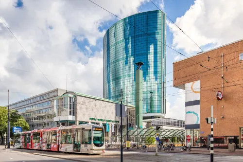 Street-level view of the Postillion Hotel & Convention Centre at the World Trade Center Rotterdam with tram passing in front.