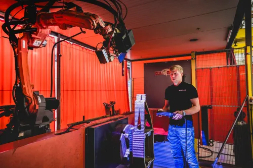 Technician at RAMLAB in Rotterdam operating a robotic 3D printing system for industrial innovation.