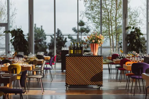 Lichte eetruimte van restaurant Renilde met houten tafels, kleurrijke stoelen en grote ramen met uitzicht over Rotterdam.