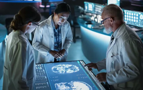 Photo of three doctors checking x rays of a head and discussing