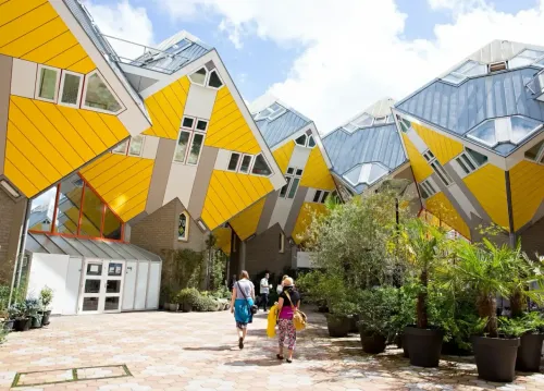 Stayokay hostel in the Cube Houses in Rotterdam, with iconic yellow cube-shaped buildings and visitors walking through the courtyard.